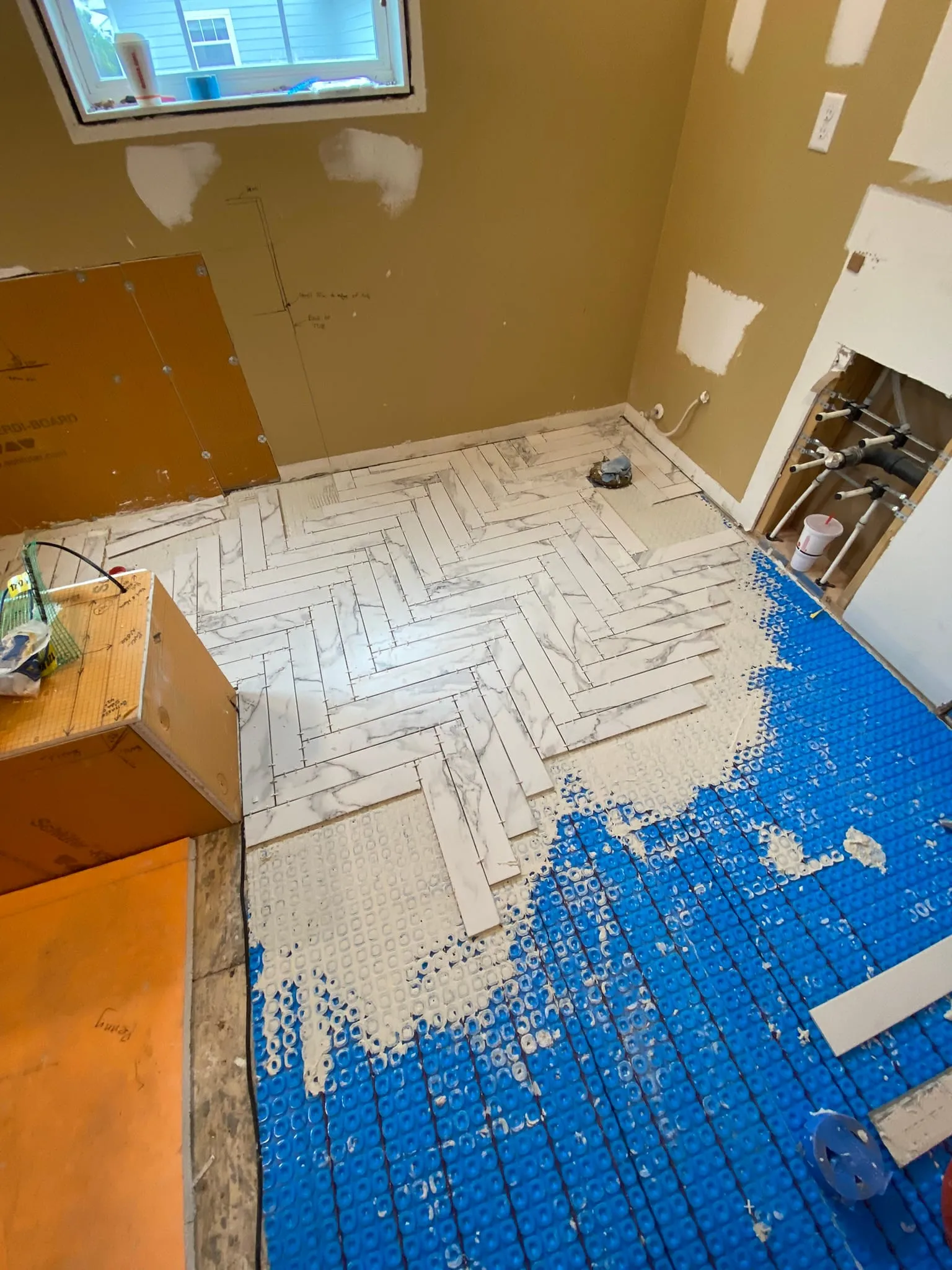 Herringbone floor tile being installed over membrane