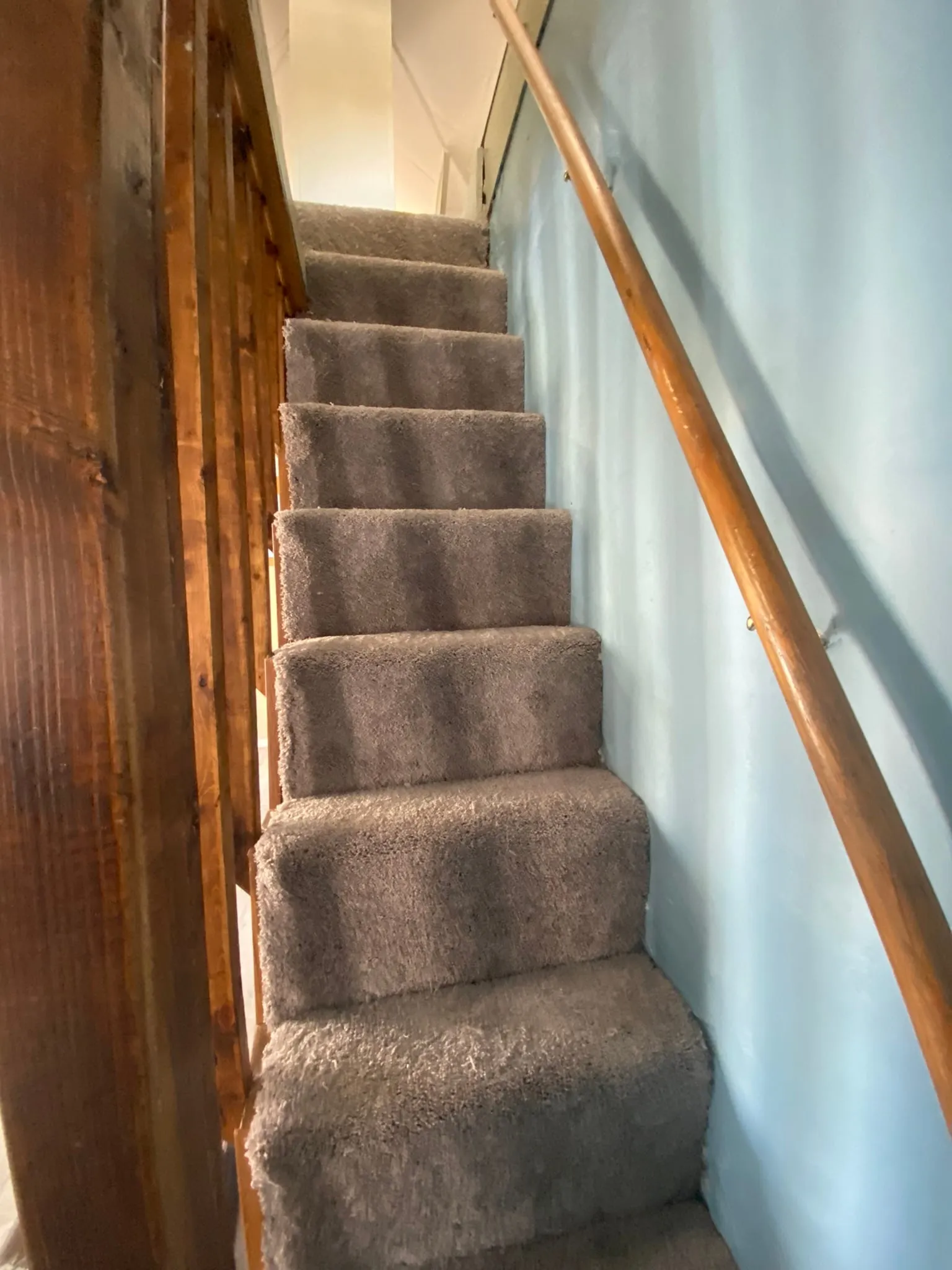 New carpeted staircase with wood handrail