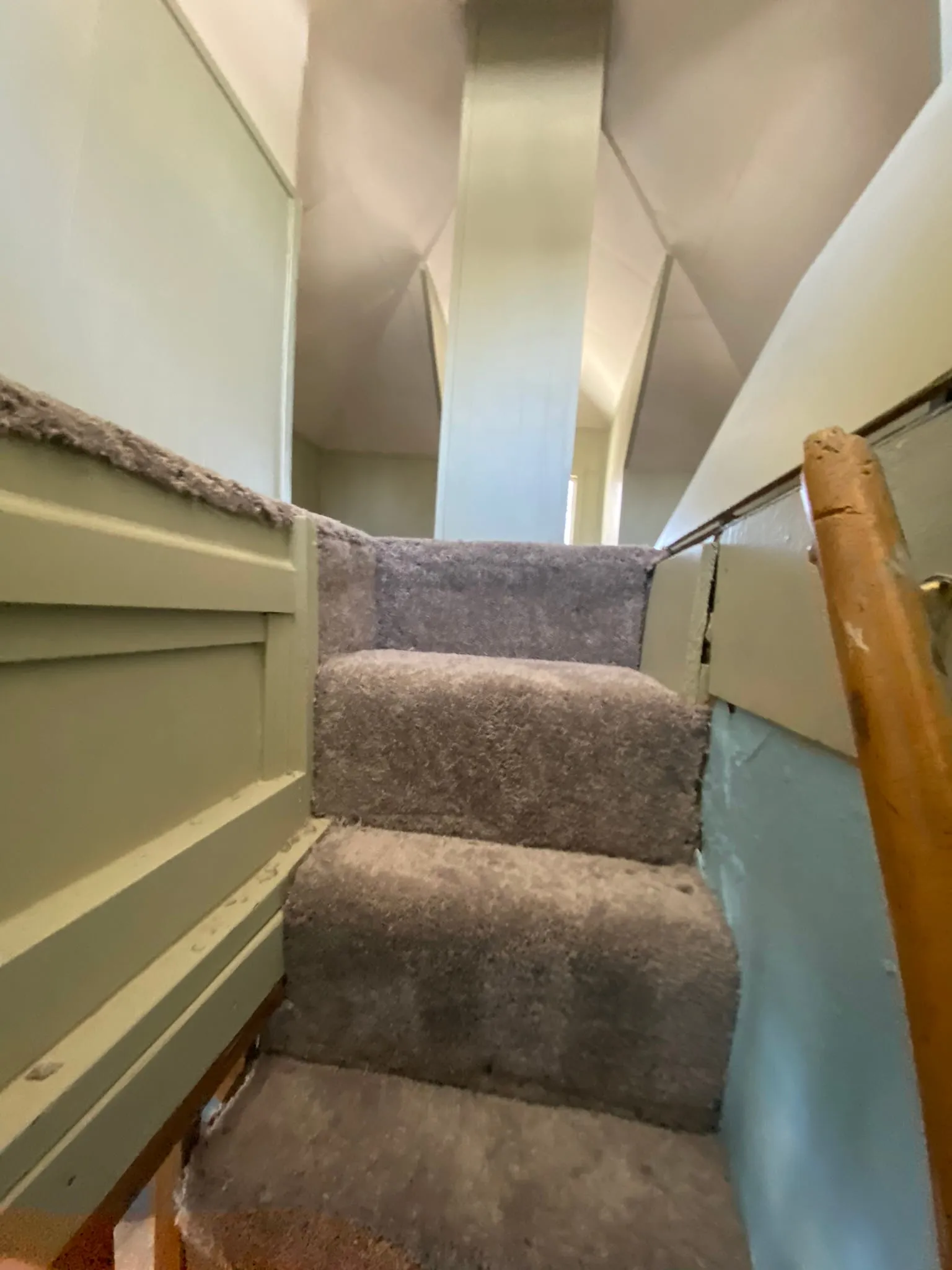 Carpeted stairs with painted wainscot