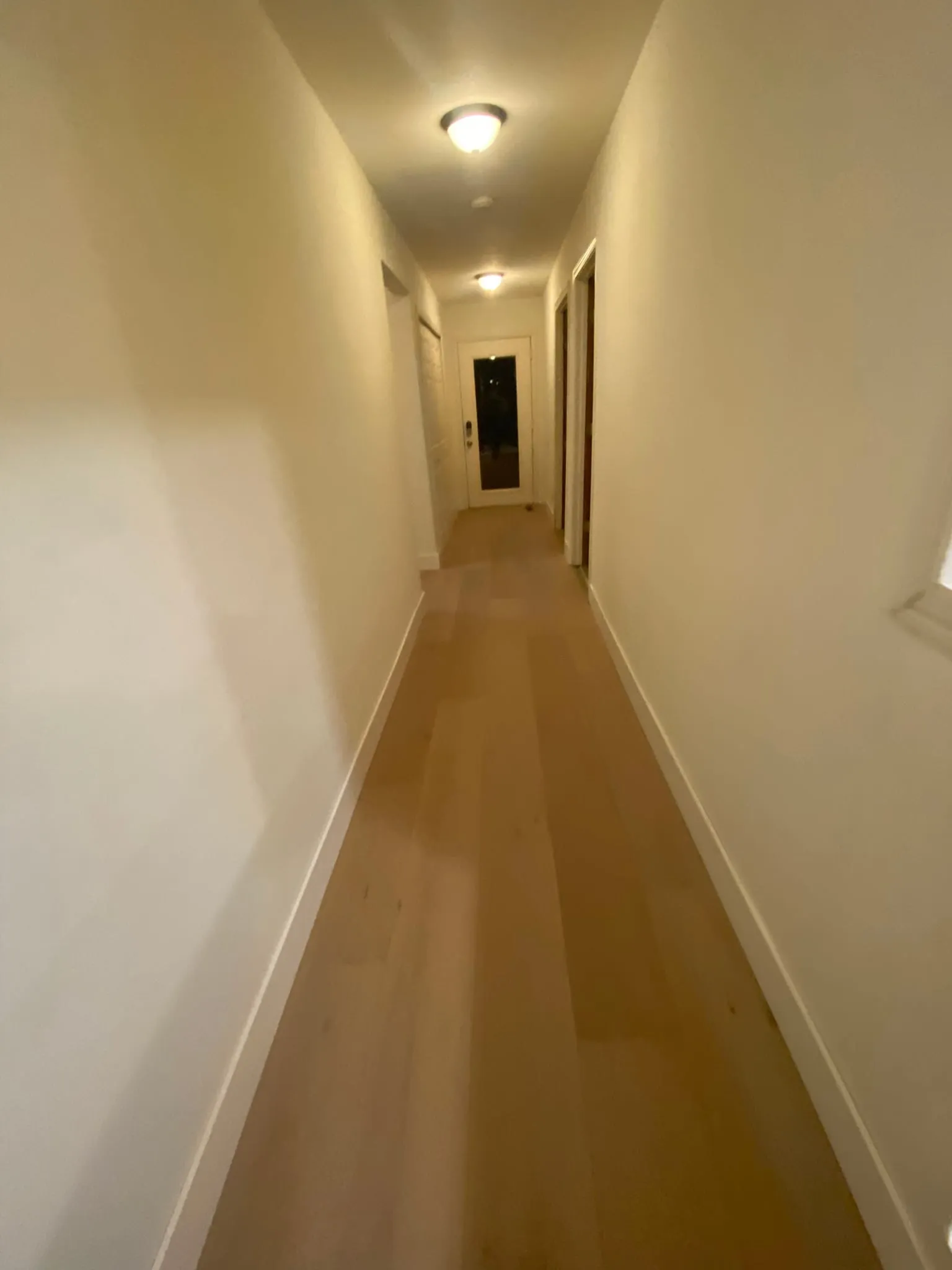 Long hallway with light hardwood flooring