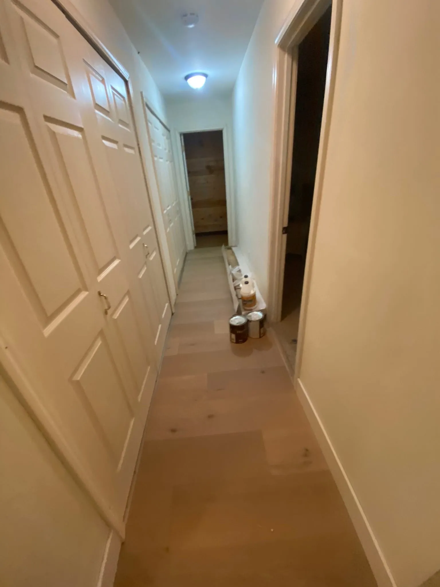 Hallway hardwood install with stain cans